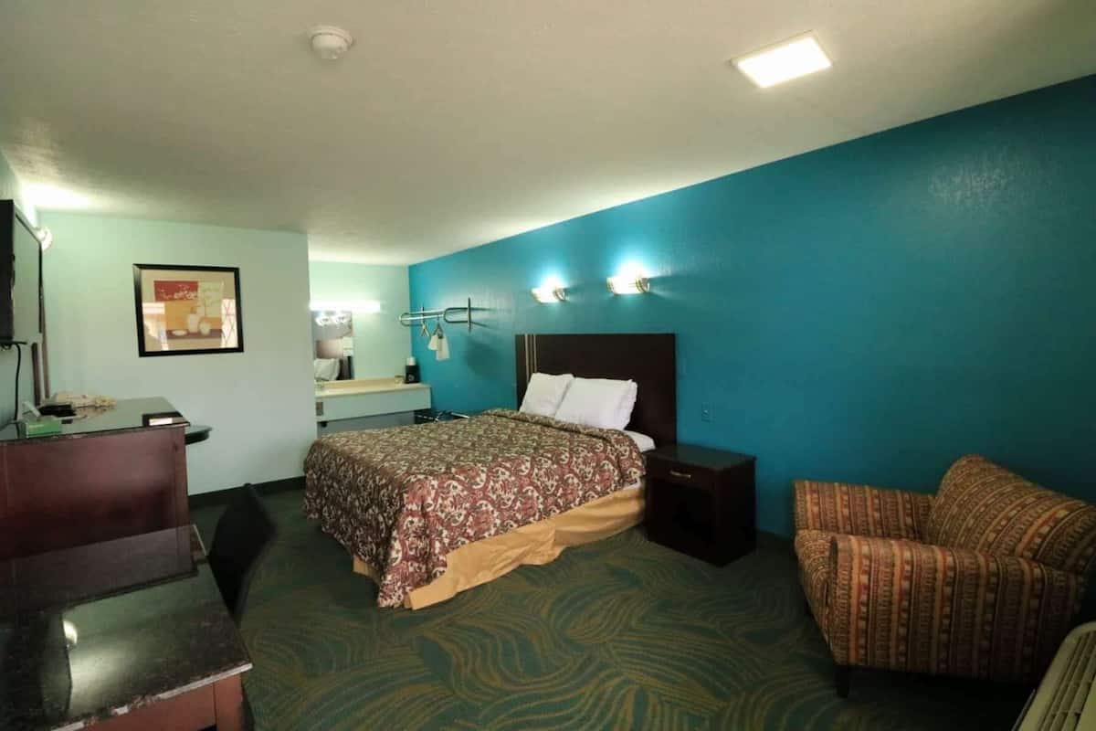 A hotel room with a bed, a desk, a chair, and a bathroom.