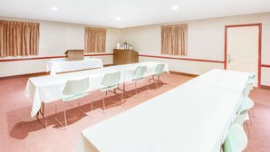 Sala de conferências com mesas compridas, cadeiras, um púlpito e uma porta.