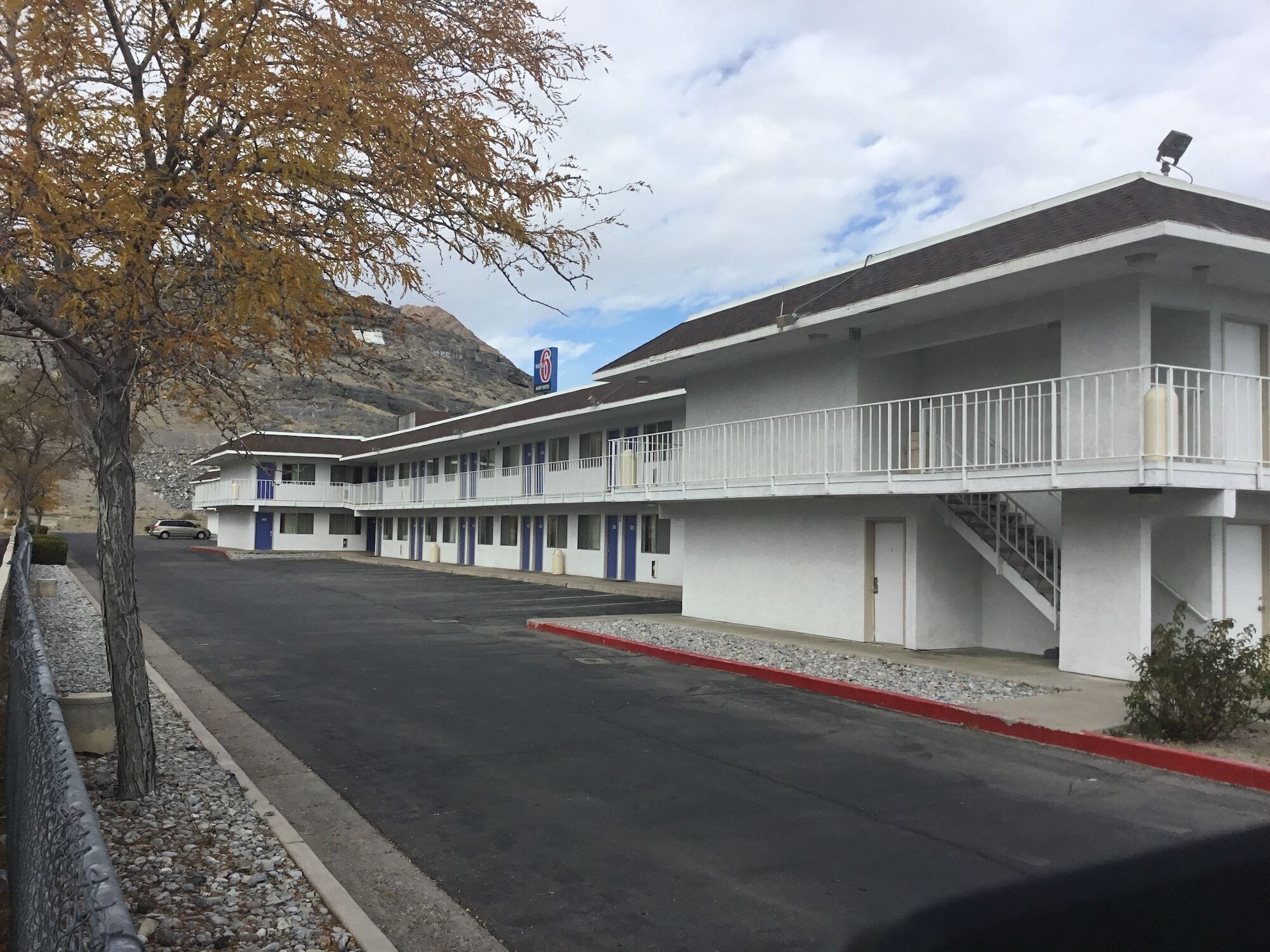 Ein Motel mit zweistöckiger Bebauung, einem Parkplatz und einem Berg im Hintergrund.