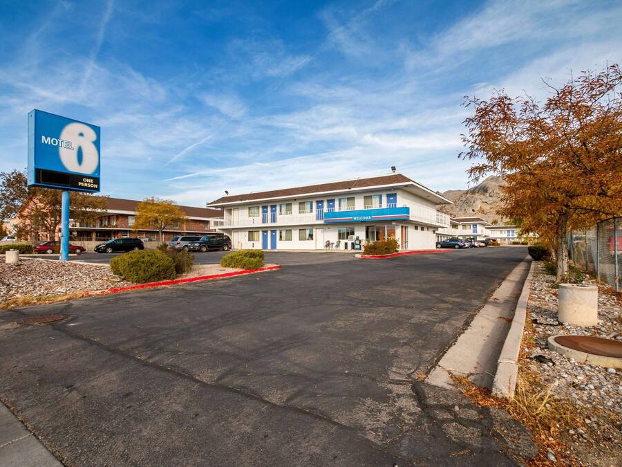 A motel with a large sign, a welcoming entrance, and a parking lot.