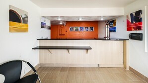 A reception area with a wooden counter, a bench, and a wall-mounted TV.