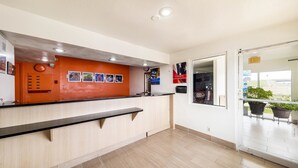 A reception area with a wooden counter, a clock, and a window with a view of the outside.