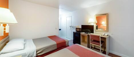Habitación de hotel con dos camas, un escritorio, una silla, un televisor y un espejo.