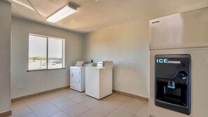 Un cuarto de lavandería con dos lavadoras, un ventanal grande y un dispensador de hielo.