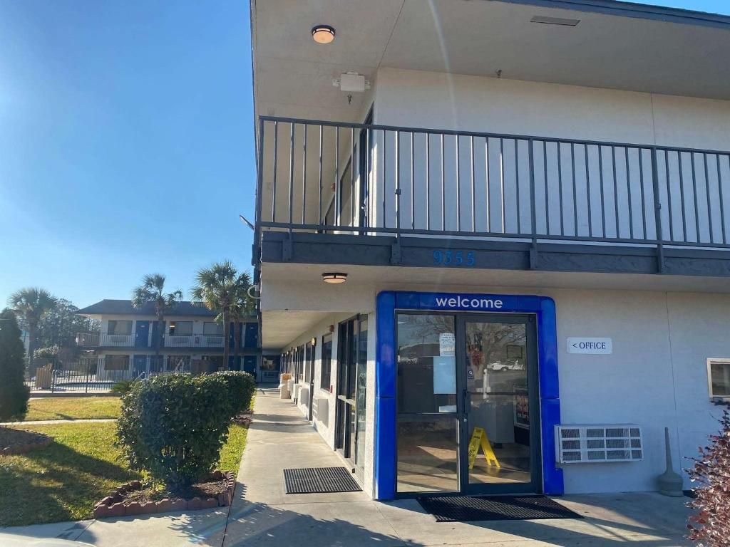 A building entrance with a blue sign reading 'welcome,' a balcony, and a sign indicating an office.