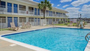 A hotel with a swimming pool, lounge chairs, and a fenced area. - Motel 6 Gulfport, MS – Airport (Gulfport)