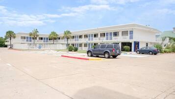 A motel with a two-story structure, a parking lot, and a clear sky.