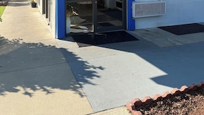 A building entrance with a blue 'welcome' sign, a '9355' address sign, and a 'less office' sign. - Motel 6 Gulfport, MS – Airport (Gulfport)