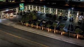 A hotel with a parking lot, a covered area, and a sign indicating it is a Quality Inn.