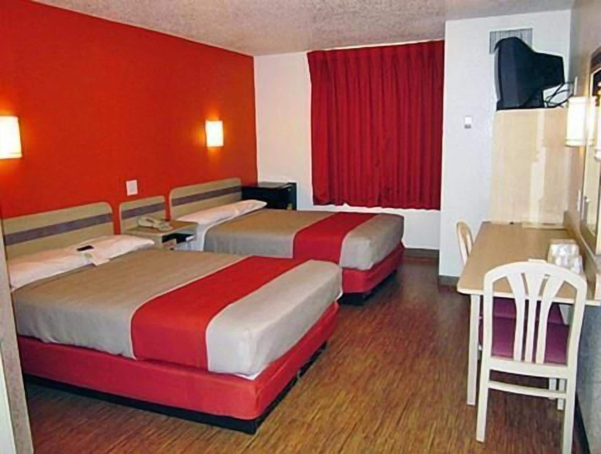 Habitación de hotel con dos camas, un escritorio y una silla.