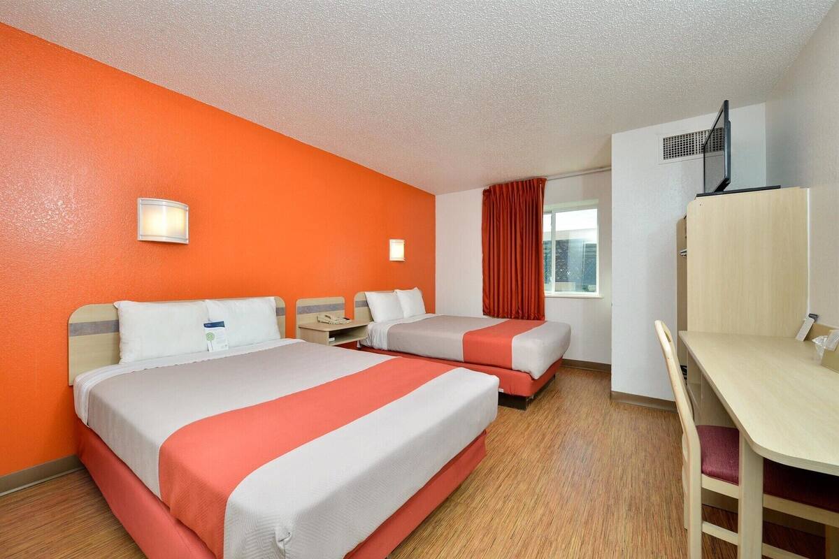 Una habitación de hotel con dos camas, un escritorio y una silla.