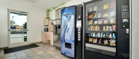 A vending machine area with a 'COLD DRINKS' dispenser and a 'PUSH' button, surrounded by a tiled floor and a door leading outside.