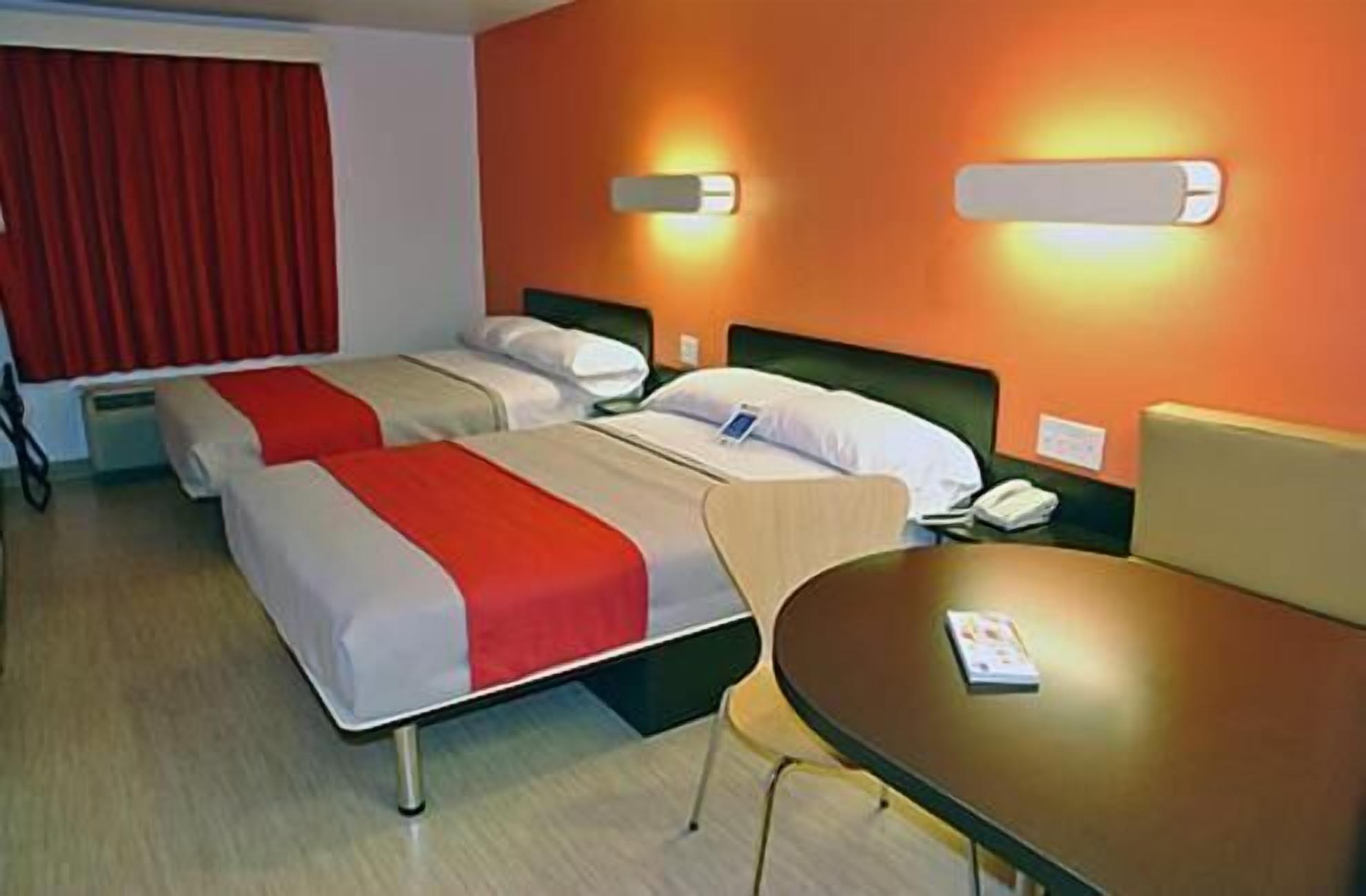 A hotel room with two beds, a table, and a chair.