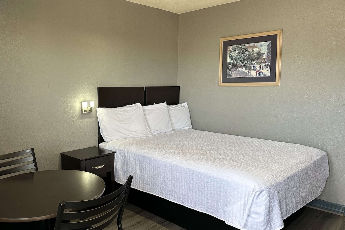 Ein Hotelzimmer mit einem Einzelbett, einem Nachttisch, einem Stuhl und einer Wandleuchte.