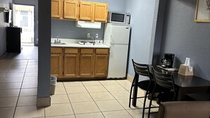 A compact kitchen with wooden cabinets, a microwave, and a refrigerator. - Americas Best Value Inn & Suites Groves Port Arthur (Groves)