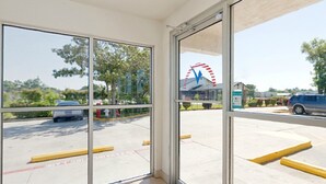 A view through a glass door of a parking area with a Ferris wheel in the background. - Americas Best Value Inn & Suites Groves Port Arthur (Groves)