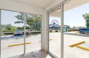 Vista a través de un ventanal de un estacionamiento con una noria al fondo.