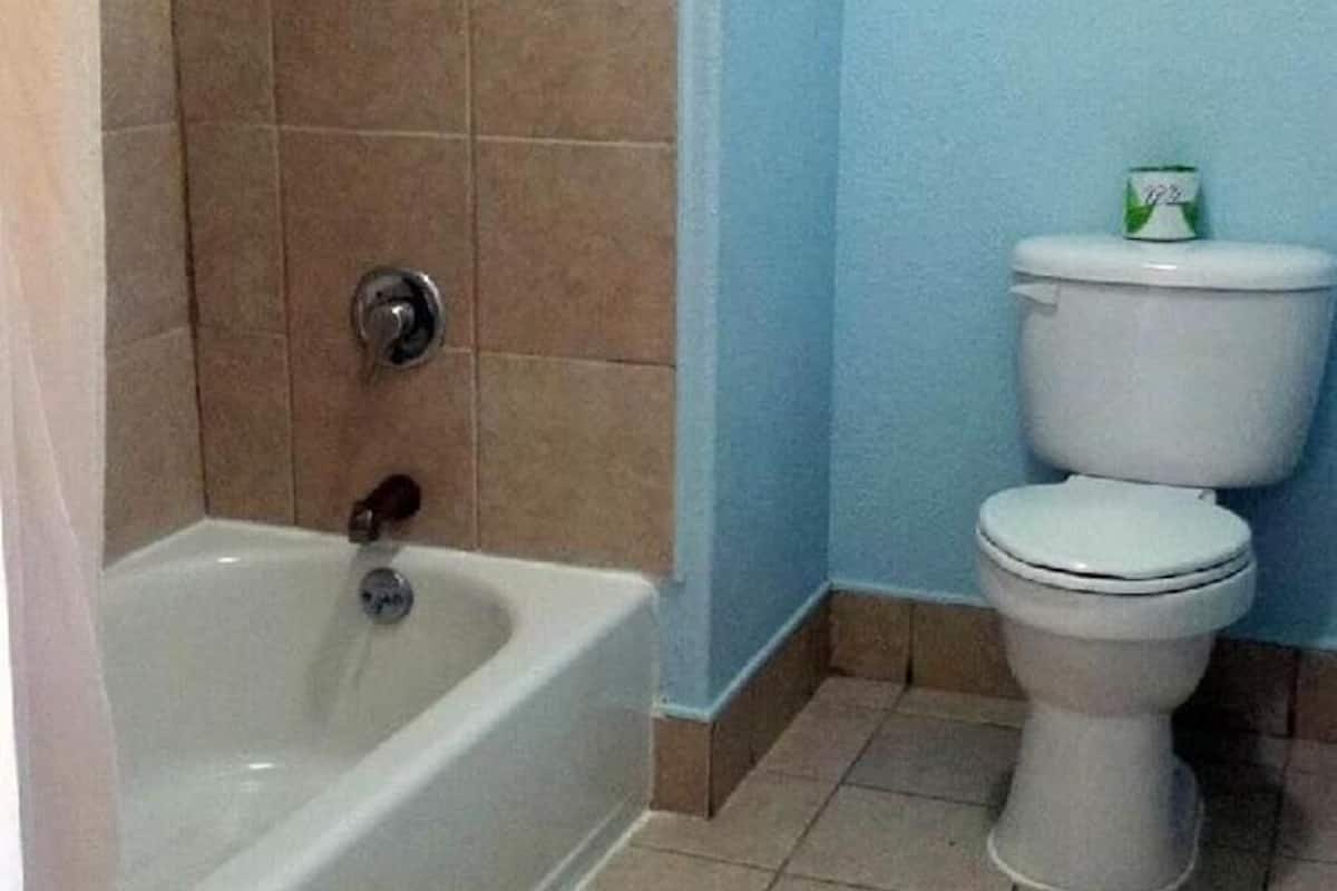 Ein Badezimmer mit einer Badewanne, Toilette und einem kleinen, grünen Mülleimer.
