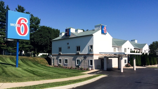 A motel with a large sign, a covered parking area, and a well-maintained lawn. - Motel 6 Gordonville PA - Lancaster PA (Gordonville)