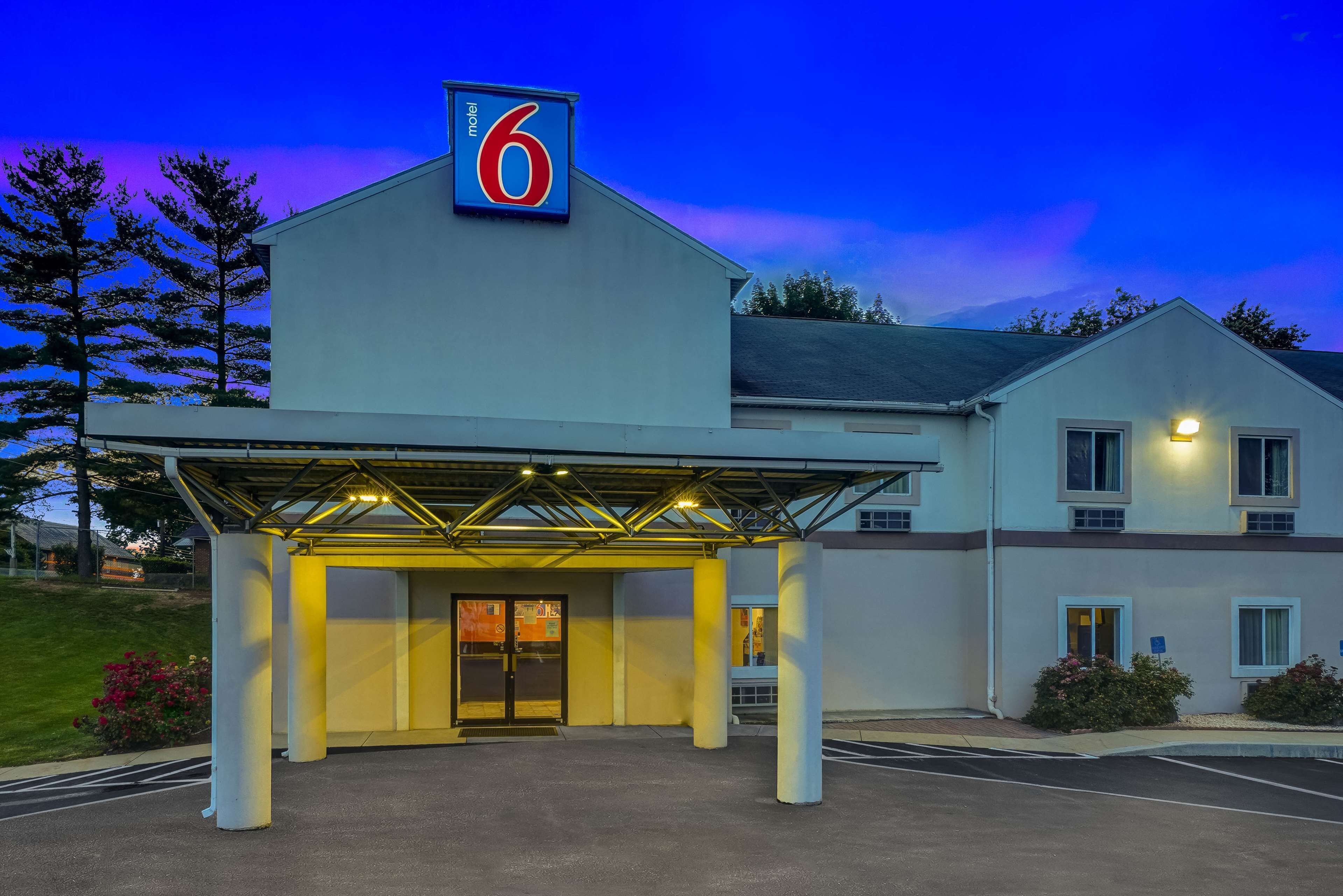 A motel with a prominent '6' sign, a covered entrance, and a parking lot.