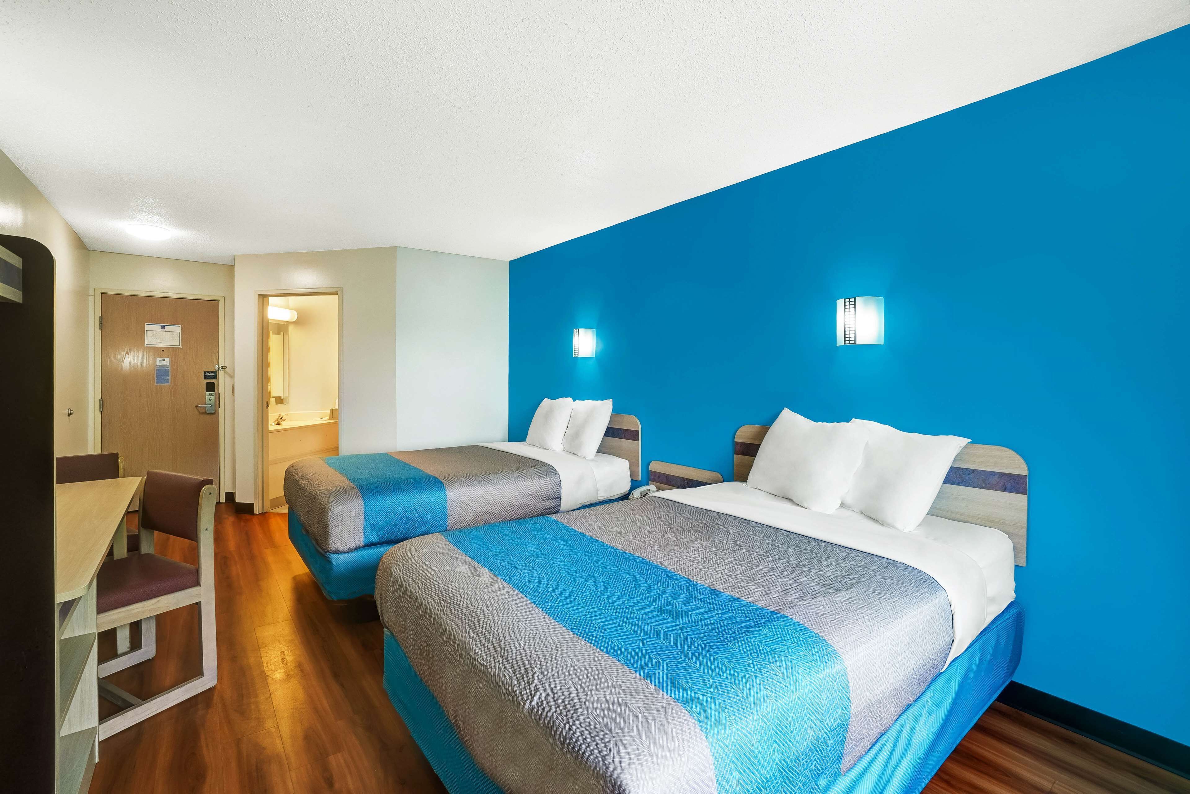 A hotel room with two beds, a desk, and a chair.
