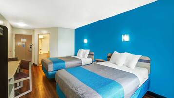 A hotel room with two beds, a desk, and a chair.