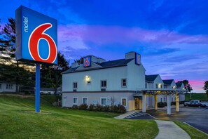 Stay at this Motel 6, featuring a flat roof and covered parking area, surrounded by well-maintained grass and trees.