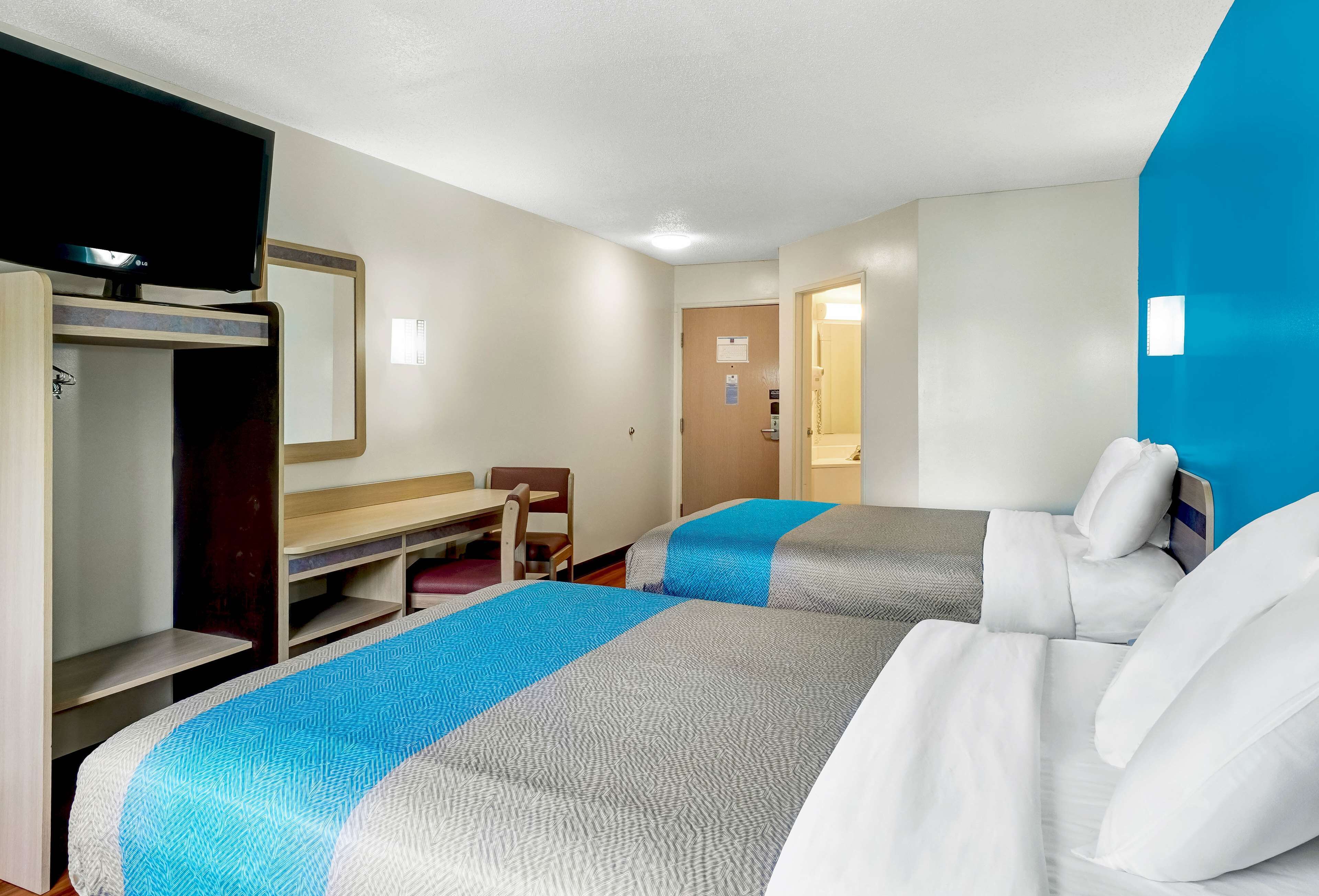 A hotel room with two beds, a desk, a chair, a TV, and a wardrobe.
