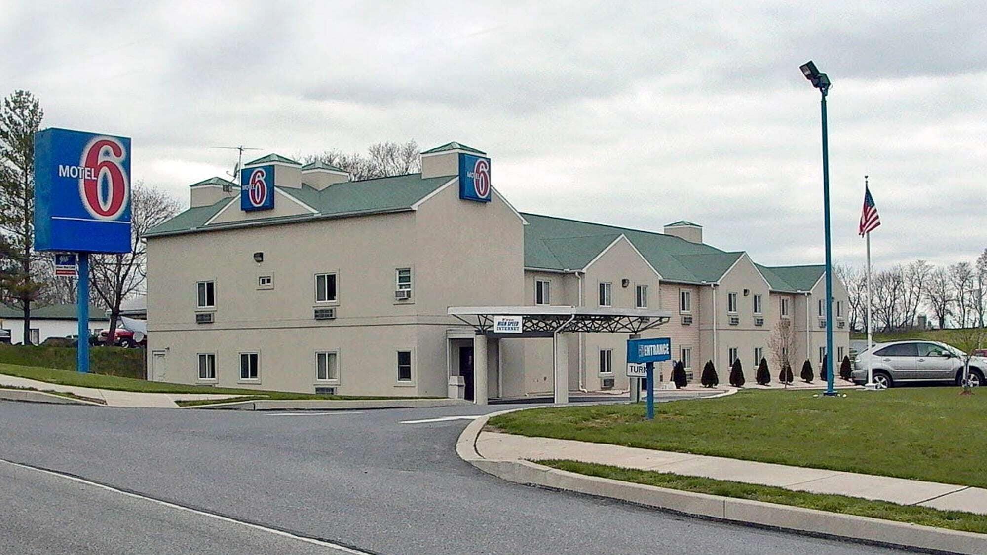 Ein Motel 6 Gebäude mit einem grünen Dach, zahlreichen Fenstern und einer Eingangstafel.