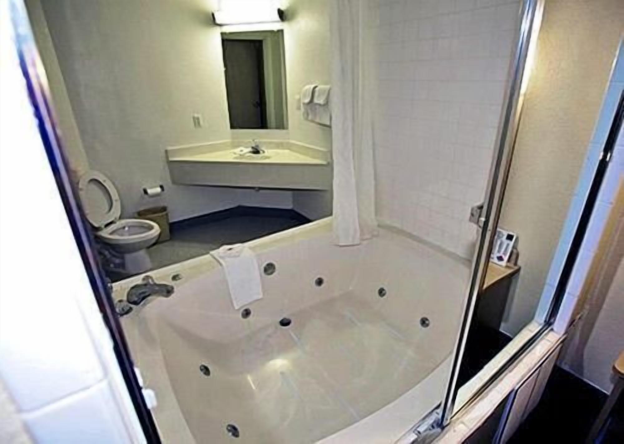 A bathroom with a bathtub, toilet, sink, and mirror.