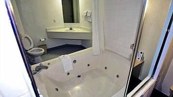 A bathroom with a bathtub, toilet, sink, and mirror.