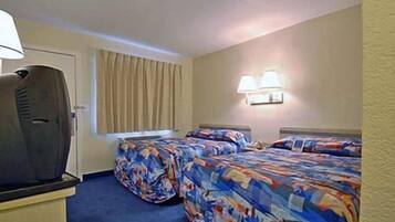 Habitación de hotel con dos camas, televisión y ventana con cortinas.