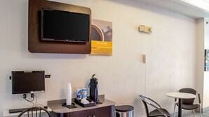 A hotel room with a TV, a coffee machine, a small cabinet, and two chairs. - Motel 6 Seymour, IN - North (Seymour)