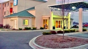 A motel with a '6' sign, a covered parking area, and a landscaped entrance. - Motel 6 Seymour, IN - North (Seymour)