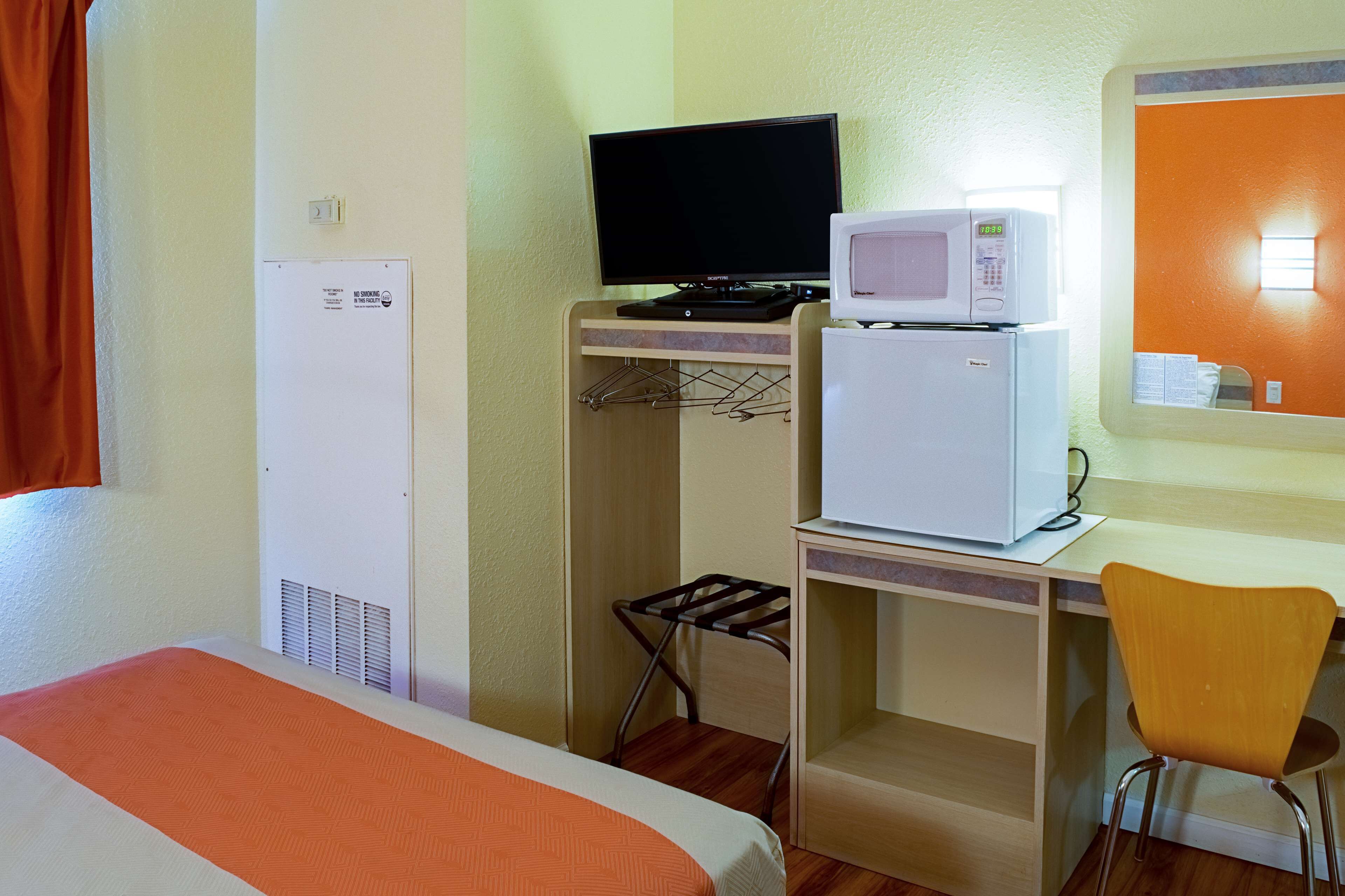 Une chambre d’hôtel équipée d’un lit, d’un bureau avec un ordinateur et un four à micro-ondes, d’une chaise et d’une armoire.