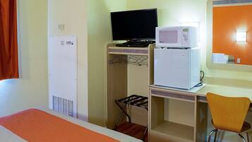 Une chambre d’hôtel équipée d’un lit, d’un bureau avec un ordinateur et un four à micro-ondes, d’une chaise et d’une armoire.