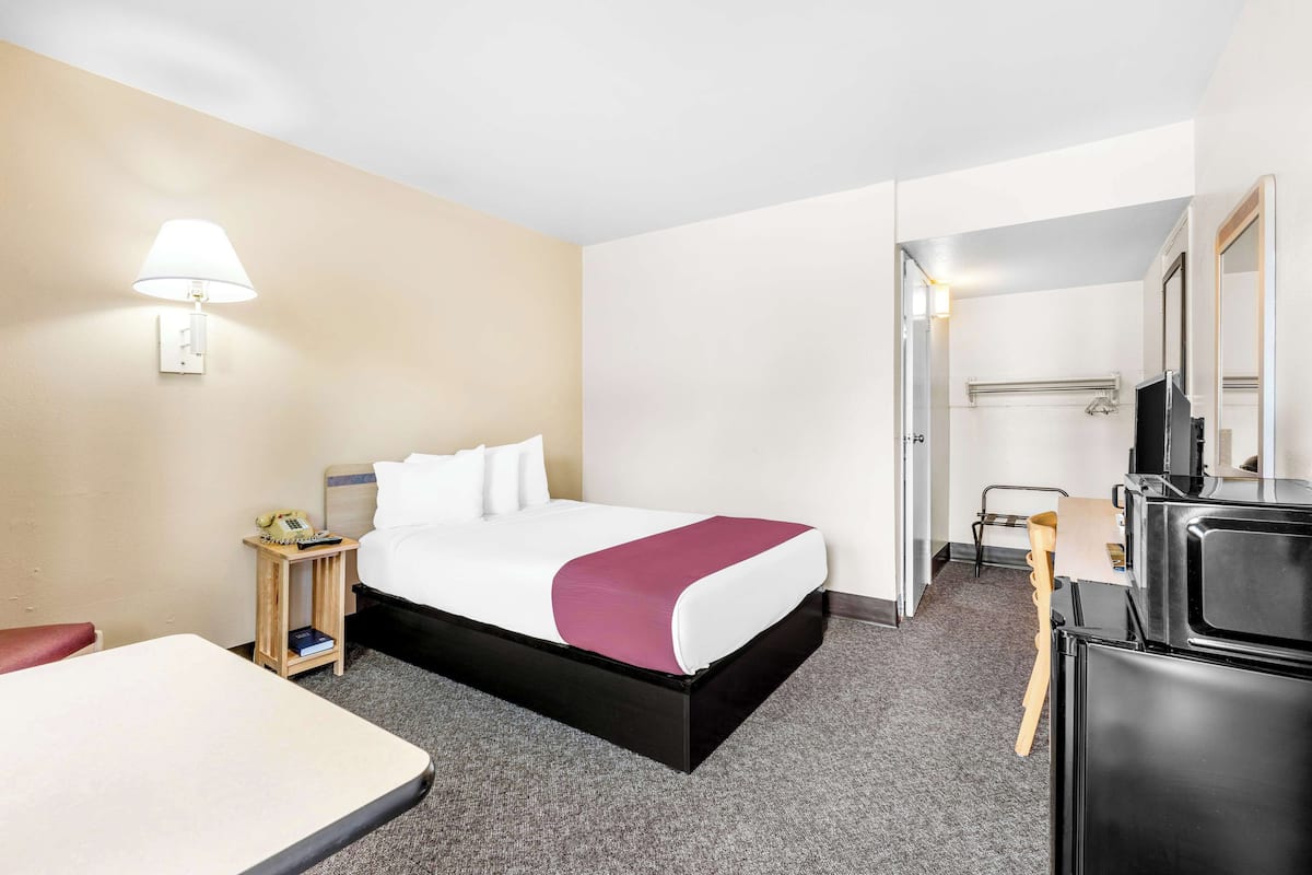 Une chambre d’hôtel équipée d’un lit, d’une table de chevet, d’une lampe et d’un téléviseur.