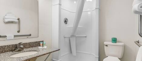 A bathroom with a shower, sink, toilet, and a towel rack.