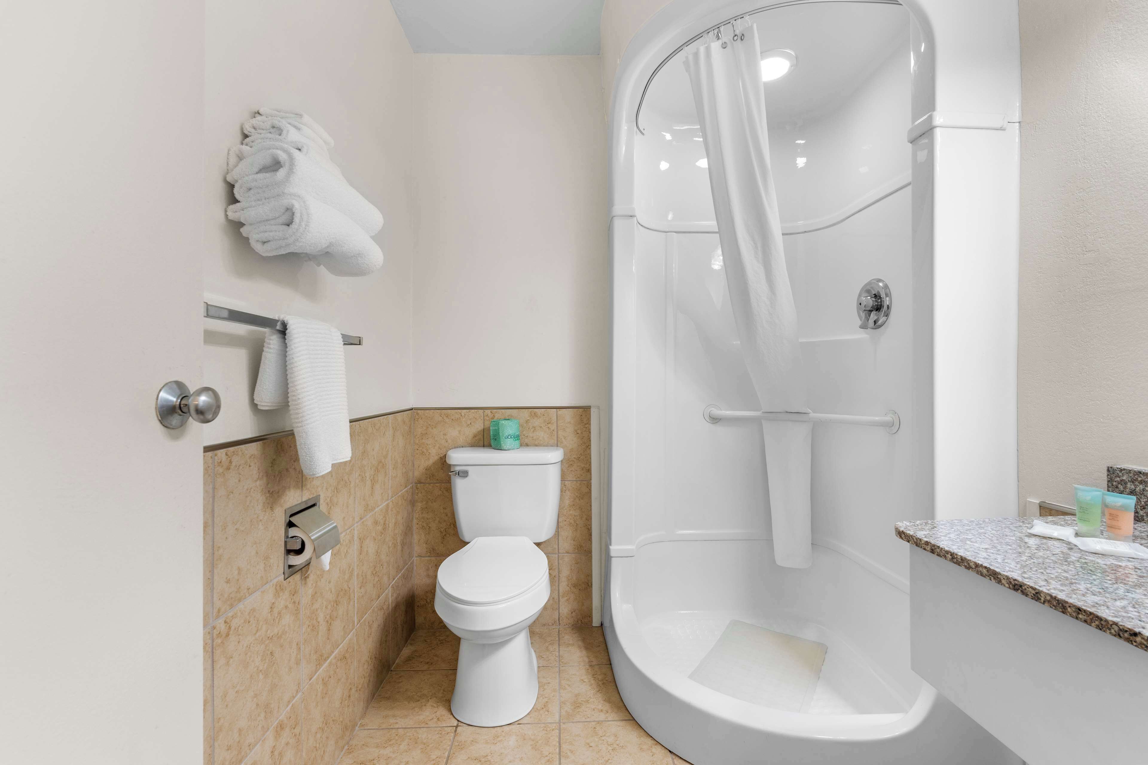 A modern bathroom with a toilet, shower, and sink.