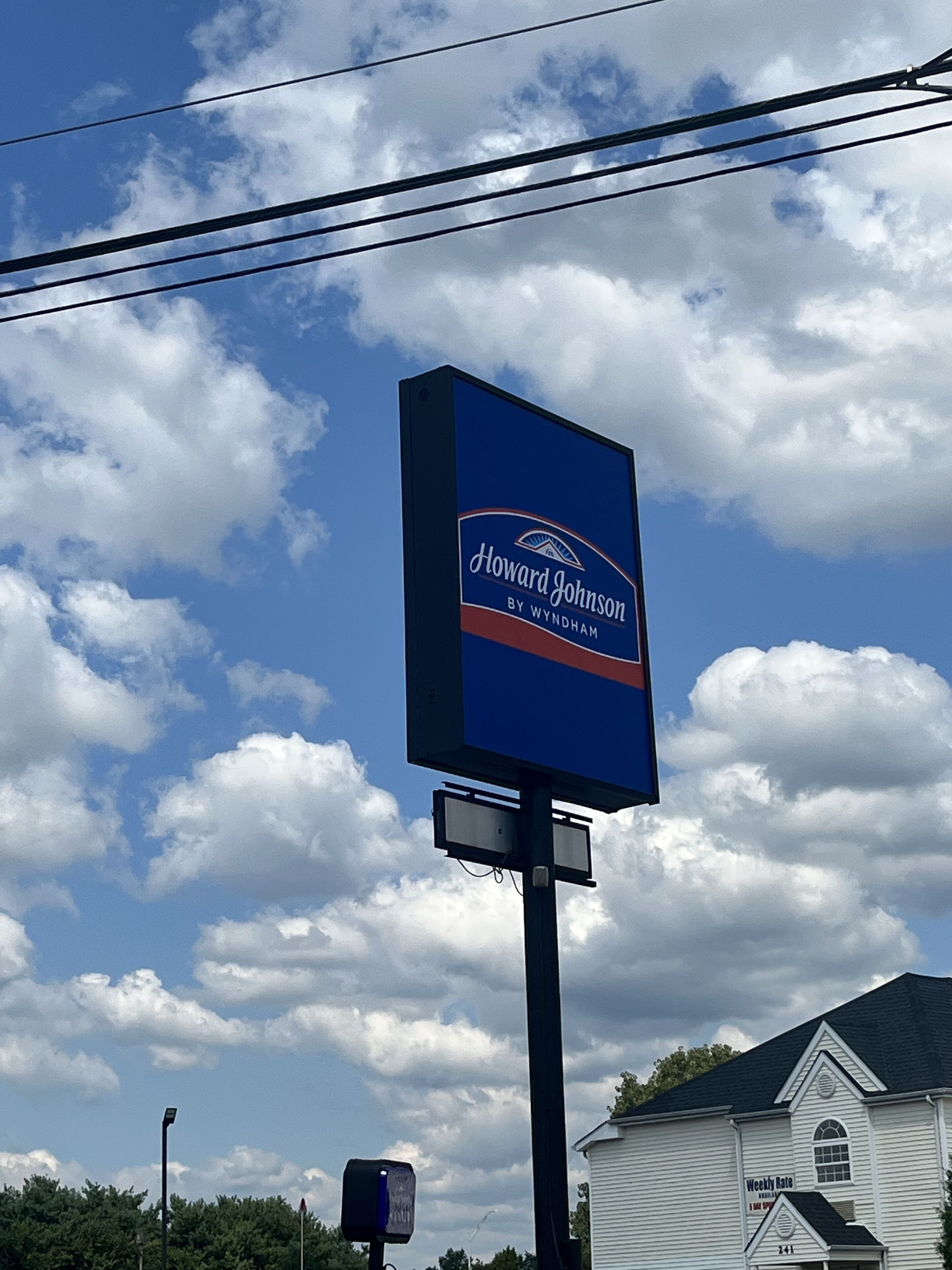 Un letrero de Howard Johnson, con un cielo azul despejado y nubes al fondo.