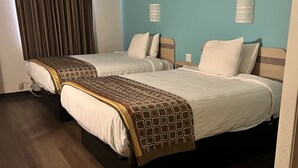 A hotel room with two beds, wooden flooring, a blue accent wall, and a window with curtains. - Howard Johnson by Wyndham Clarksville Tennessee (Clarksville)
