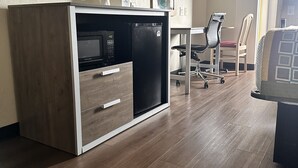 A modern room with a kitchenette, a flat-screen TV mounted on the wall, and a wooden floor. - Howard Johnson by Wyndham Clarksville Tennessee (Clarksville)