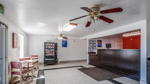A hotel lobby with a reception desk, seating area, vending machine, and ceiling fans. - Motel 6 Beaver, UT (Beaver)