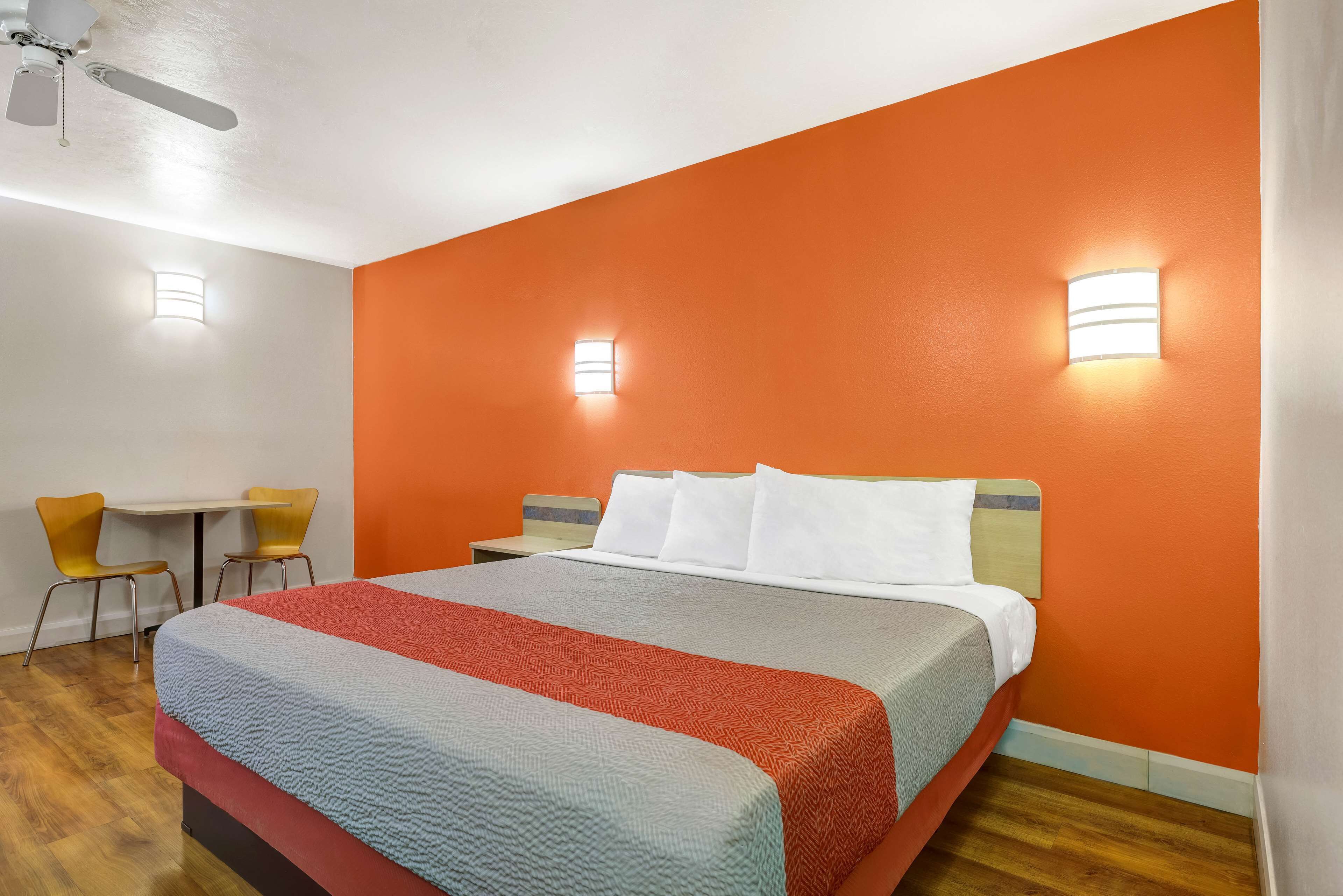 A hotel room with a large bed, two bedside tables, a desk, and two chairs.