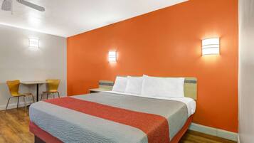 A hotel room with a large bed, two bedside tables, a desk, and two chairs.