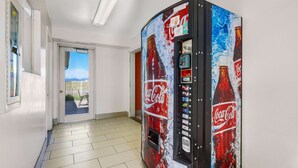 A Coca-Cola vending machine in a hallway with a view of a balcony. - Motel 6 Beaver, UT (Beaver)