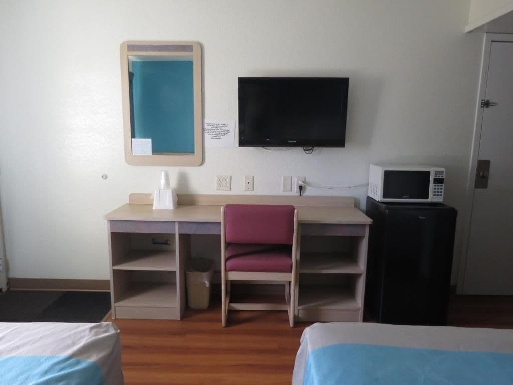 Una camera d'albergo con un letto, una scrivania con una sedia, una televisione e un forno a microonde.