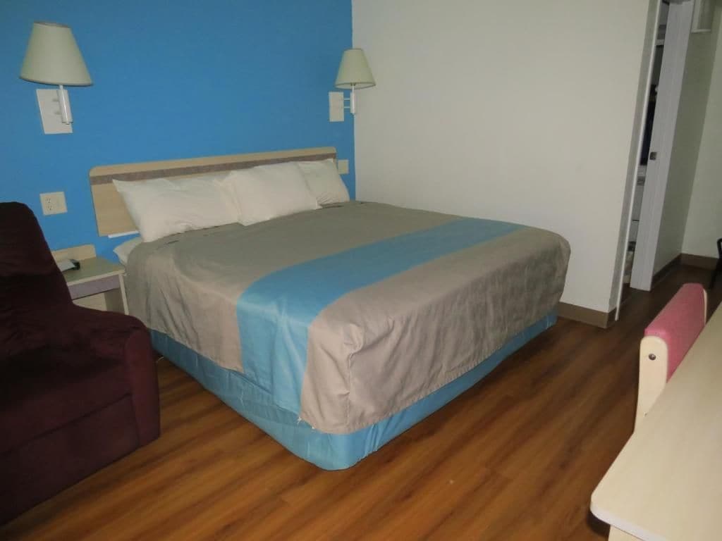 Una habitación con cama, una silla, una lámpara y una puerta.