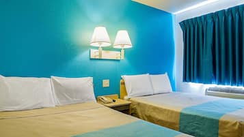 Una habitación de hotel con dos camas, una mesita de noche con teléfono y una lámpara fijada a la pared.