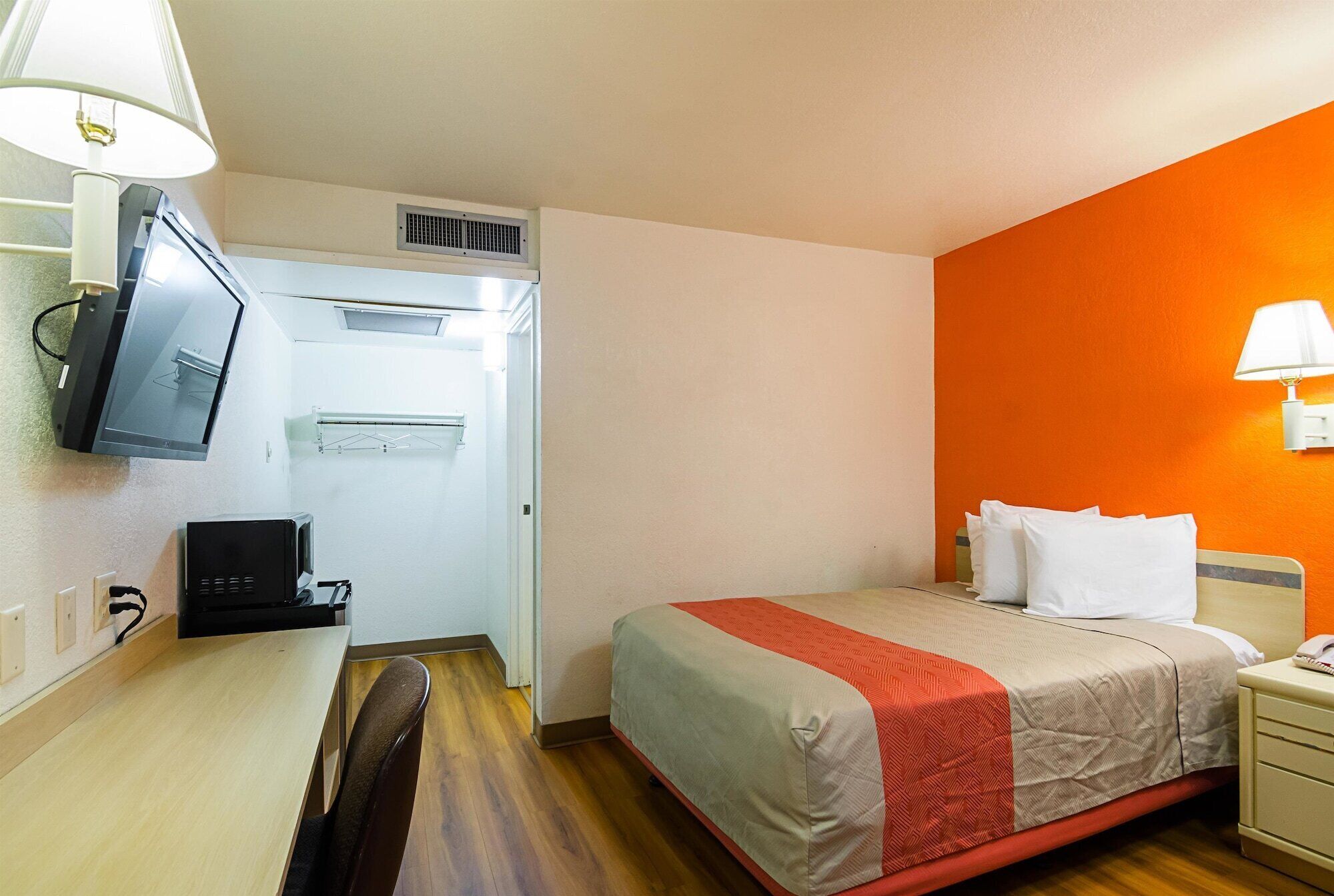 A hotel room with a bed, a desk with a computer, a TV, and a heater.